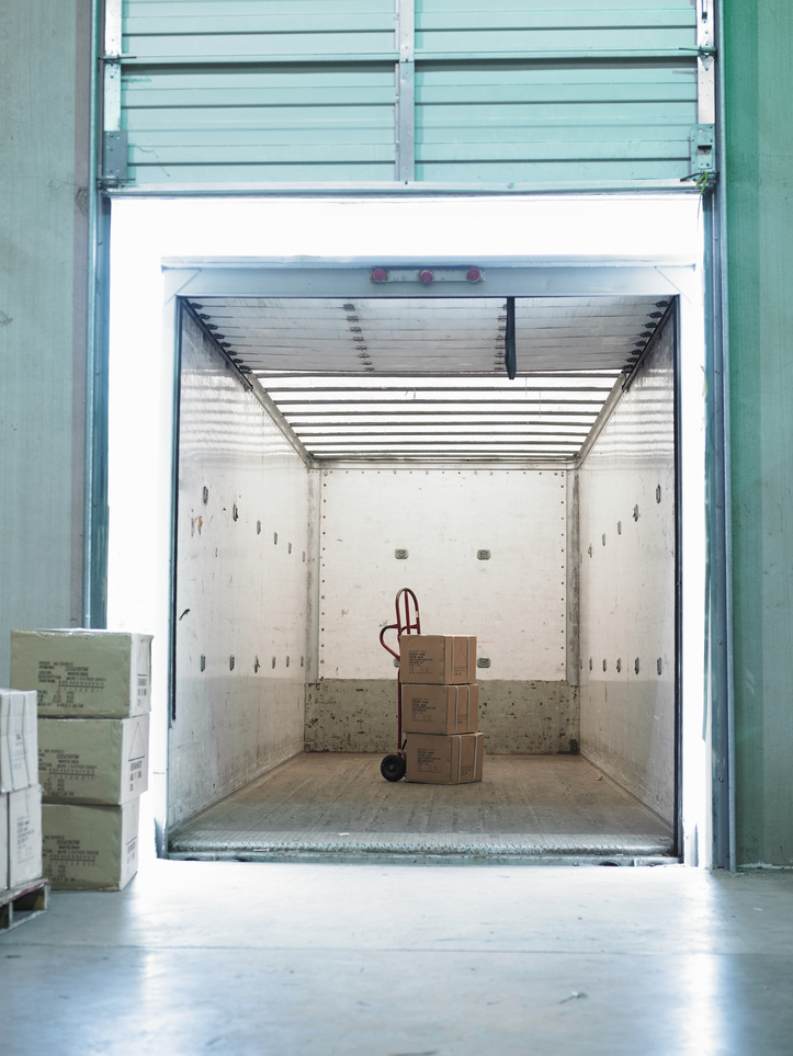 Hand truck and boxes inside semi-truck at loading dock